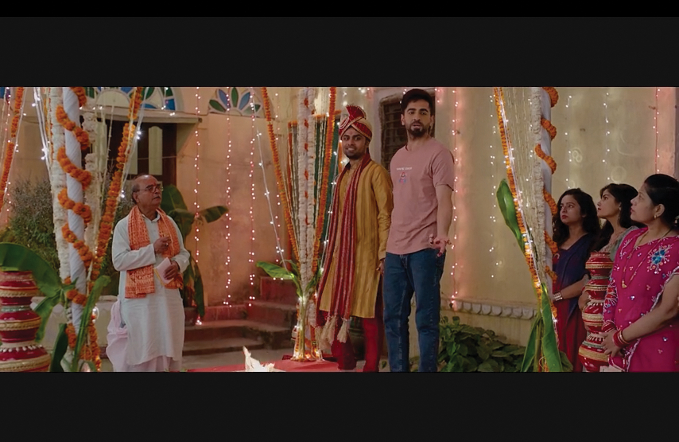 Aman and Kartik stand together holding hands and singing.